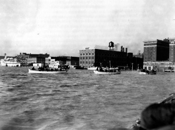 U.S. Coast Guard cutters on Dress Plaza, approaching the city. Steamboat and barges beyond them. Identifiable buildings are Keller Crescent Printing & Engraving Co. at 24-28 SE Riverside Dr., Hotel McCurdy at 101-11 SE 1st St., and in front of the hotel, the Graham Motor Cars distributorship owned by Robert W. Baskett at 118 SE Riverside Drive, 1937. Source: Flood of 1937 collection (MSS 272-0765)