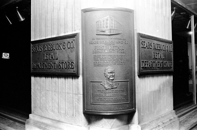 Plaque on side of building detailing historic site of former Sears and Robuck Company retail store at 101 NW 4th Street. The sign's wording is misleading---this is not the site of Sears's first retail department store---that was in Chicago. This is the first store outside of a Catalog Merchandise Distribution Center. At the time of this photograph, the Sears store had long since (1963) moved to its 100 South Green River Road. address in Washington Square Mall, 1976. Source: Gregory Smith collection, MSS 034-0466.