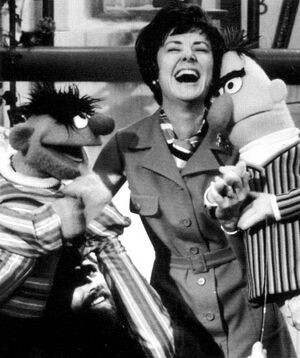 Joan Ganz Cooney sharing a laugh with                               Ernie and Bert. Source: https://muppet.fandom.com/wiki/Sesame_Street
